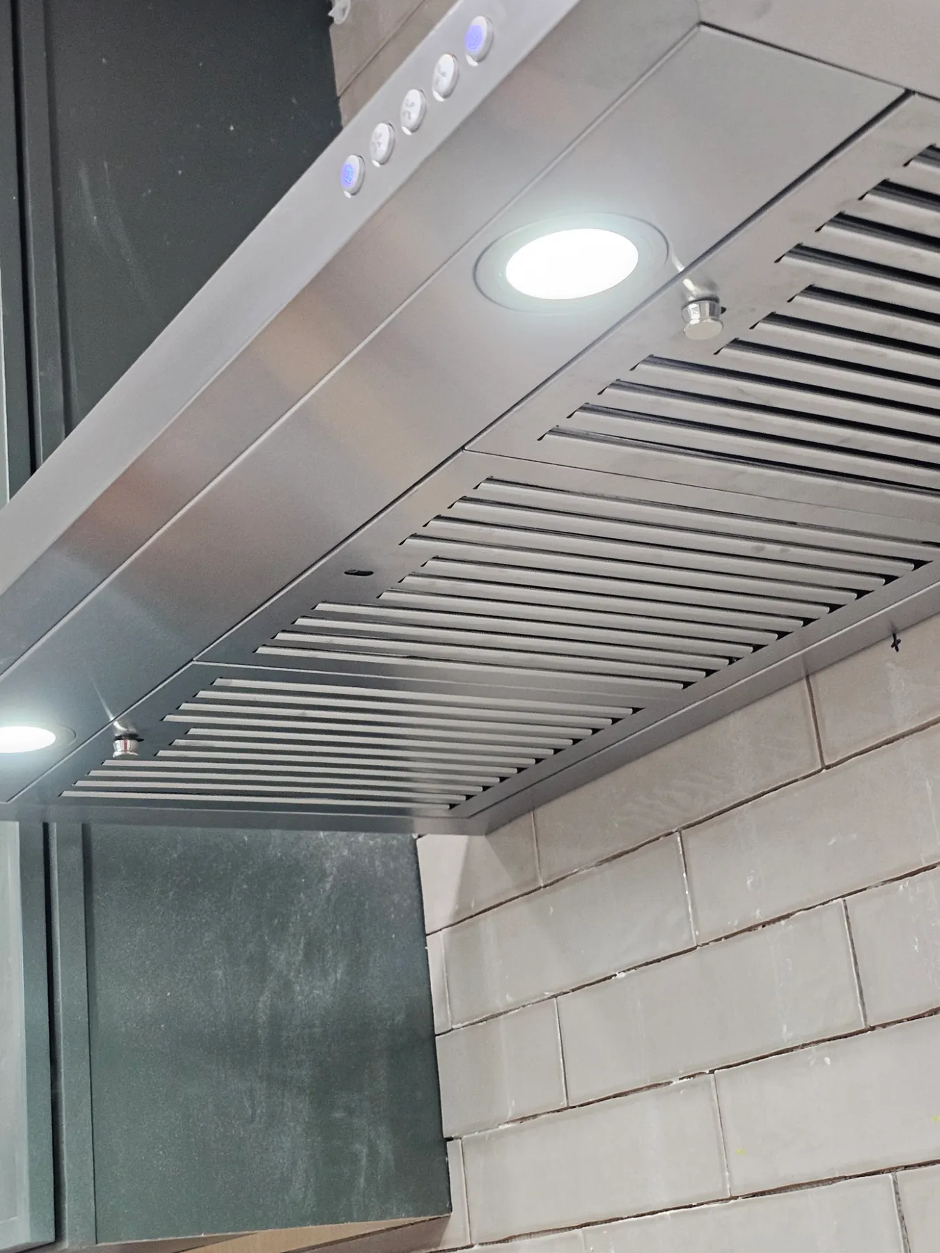 Installed stainless steel range hood with working lights
