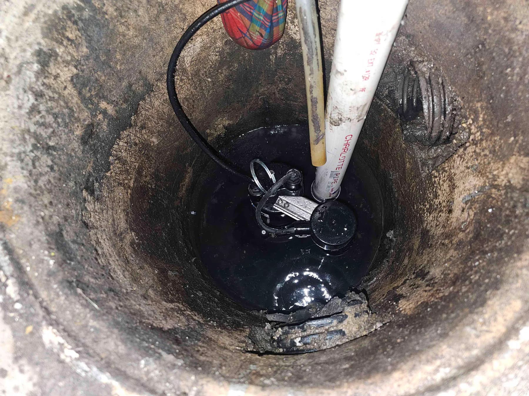Wide view of the new sump pump installation inside the basin